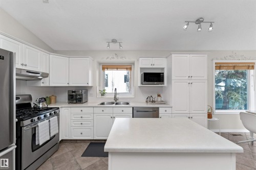 Kitchen featuring stainless steel appliances, white cabinetry, light countertops, lofted ceiling, and a kitchen island - 357 Blackburn Drive E, Edmonton, AB - Indoor Photo Showing Kitchen With Double Sink