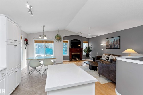 Kitchen featuring open floor plan, white cabinetry, light countertops, hanging lights, and a fireplace - 357 Blackburn Drive E, Edmonton, AB - Indoor Photo Showing Living Room With Fireplace