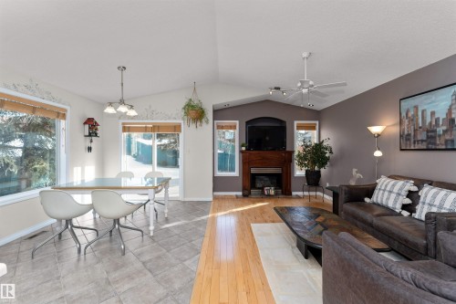 Living room with a fireplace, vaulted ceiling, light wood-type flooring, and a ceiling fan - 357 Blackburn Drive E, Edmonton, AB - Indoor With Fireplace