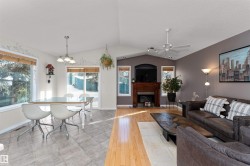 Living room with a fireplace, vaulted ceiling, light wood-type flooring, and a ceiling fan - 