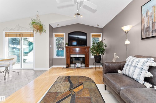 Living area with light wood finished floors, ceiling fan, and a fireplace with flush hearth - 357 Blackburn Drive E, Edmonton, AB - Indoor Photo Showing Living Room With Fireplace