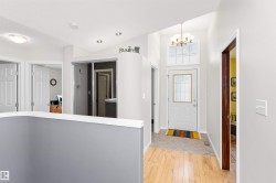 Foyer featuring light wood finished floors and hanging lights - 
