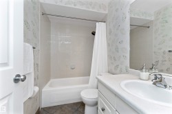Bathroom with wallpapered walls, vanity, shower / bath combo, and dark tile patterned flooring - 
