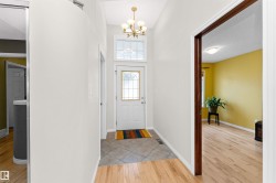 Foyer entrance with light wood-style flooring, suspended lighting, and a high ceiling - 