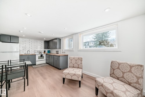 Kitchen with gray cabinets, white electric range, light wood finished floors, backsplash, and recessed lighting - 8712 89 Avenue, Edmonton, AB - Indoor