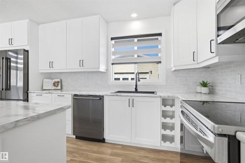 Kitchen with stainless steel appliances, white cabinets, light wood-style floors, light stone counters, and recessed lighting - 4204 41B Street, Leduc, AB - Indoor Photo Showing Kitchen With Upgraded Kitchen