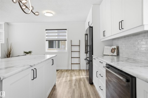 Kitchen with white cabinetry, dishwasher, light wood-type flooring, high end fridge, and hanging lights - 4204 41B Street, Leduc, AB - Indoor Photo Showing Kitchen