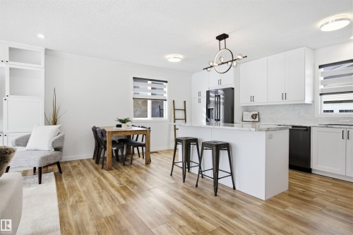 Kitchen featuring a center island, white cabinets, a kitchen bar, stainless steel refrigerator with ice dispenser, and a textured ceiling - 4204 41B Street, Leduc, AB - Indoor Photo Showing Kitchen With Upgraded Kitchen