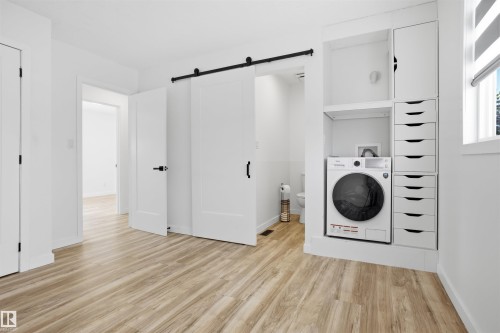 Laundry area with a barn door, washer / clothes dryer, and light wood-style flooring - 4204 41B Street, Leduc, AB - Indoor Photo Showing Laundry Room