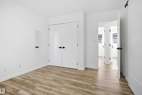 Unfurnished bedroom featuring a closet, light wood-style floors, and a barn door - 4204 41B Street, Leduc, AB - Indoor Photo Showing Other Room
