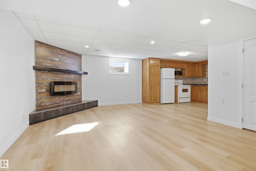 Unfurnished living room featuring light wood finished floors, a paneled ceiling, and a large fireplace - 4204 41B Street, Leduc, AB - Indoor With Fireplace