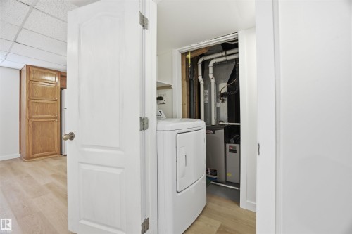 Laundry area with light wood-type flooring, washer / dryer, heating unit, and a drop ceiling - 4204 41B Street, Leduc, AB - Indoor Photo Showing Laundry Room