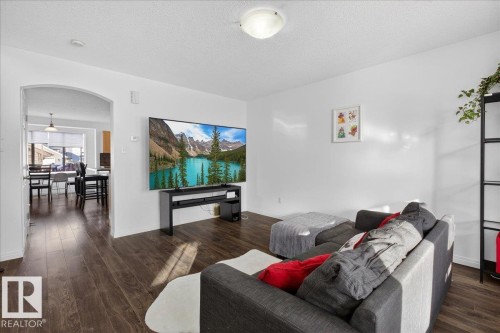 Living area featuring arched walkways, dark wood-style flooring, and a textured ceiling - 4519 Turner Square Square, Edmonton, AB - Indoor Photo Showing Living Room