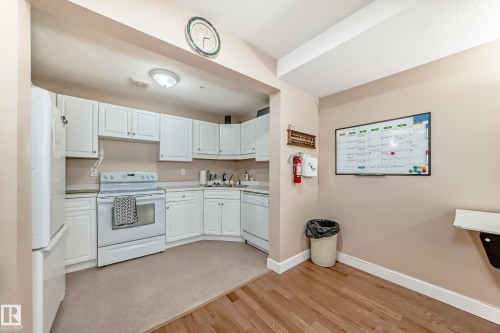 Kitchen featuring white appliances, white cabinetry, light countertops, and light wood-type flooring - 118 6220 Fulton Road, Edmonton, AB - Indoor Photo Showing Kitchen