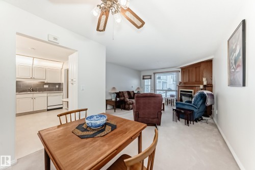Dining area featuring a ceiling fan, a glass covered fireplace, and light colored carpet - 118 6220 Fulton Road, Edmonton, AB - Indoor Photo Showing Dining Room