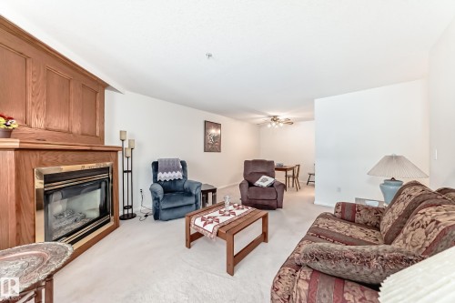 Living room featuring a glass covered fireplace, light carpet, and ceiling fan - 118 6220 Fulton Road, Edmonton, AB - Indoor Photo Showing Living Room With Fireplace