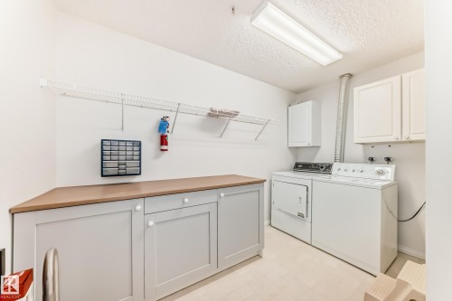 Laundry area featuring cabinet space, a textured ceiling, washer and dryer, and light floors - 118 6220 Fulton Road, Edmonton, AB - Indoor Photo Showing Laundry Room