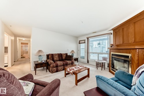 Living area with light colored carpet and a glass covered fireplace - 118 6220 Fulton Road, Edmonton, AB - Indoor Photo Showing Living Room With Fireplace