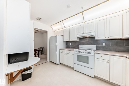 Kitchen featuring white appliances, light countertops, white cabinets, light floors, and backsplash - 118 6220 Fulton Road, Edmonton, AB - Indoor Photo Showing Kitchen