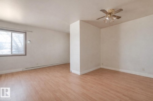 Unfurnished room featuring light wood finished floors, ceiling fan, and a baseboard heating unit - 5219 51 Avenue, Wetaskiwin, AB - Indoor Photo Showing Other Room
