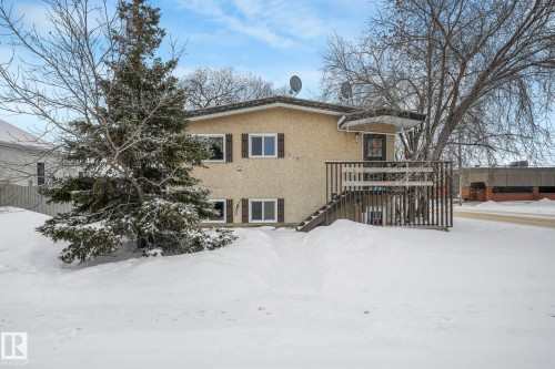 Snow covered back of property featuring stucco siding and a wooden deck - 5219 51 Avenue, Wetaskiwin, AB - Outdoor