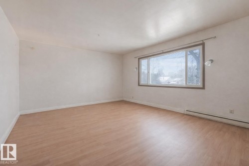Unfurnished room featuring light wood-type flooring and a baseboard radiator - 5219 51 Avenue, Wetaskiwin, AB - Indoor Photo Showing Other Room