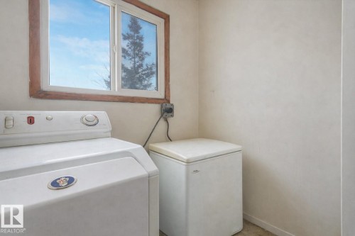Laundry area with baseboards and washing machine and clothes dryer - 5219 51 Avenue, Wetaskiwin, AB - Indoor Photo Showing Laundry Room