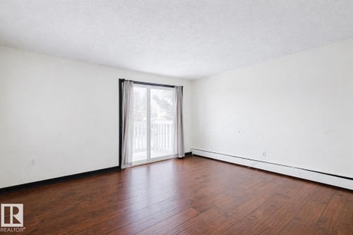 Spare room featuring a baseboard radiator, dark wood-type flooring, and a textured ceiling - 3917/3919 54 Street, Wetaskiwin, AB - Indoor Photo Showing Other Room