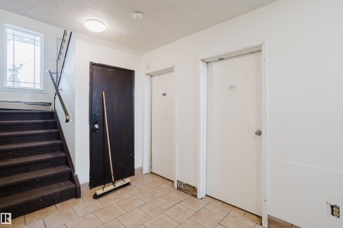 Foyer entrance featuring a textured ceiling, light tile patterned flooring, and baseboard heating - 3917/3919 54 Street, Wetaskiwin, AB - Indoor Photo Showing Other Room