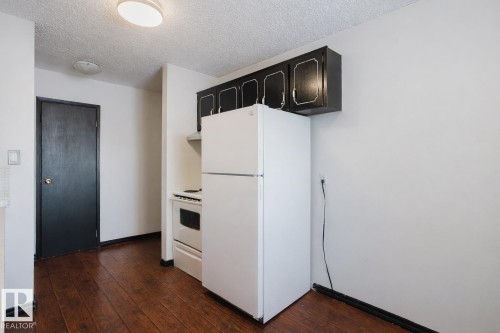 Kitchen featuring white appliances, a textured ceiling, dark wood-type flooring, light countertops, and extractor fan - 3917/3919 54 Street, Wetaskiwin, AB - Indoor Photo Showing Kitchen