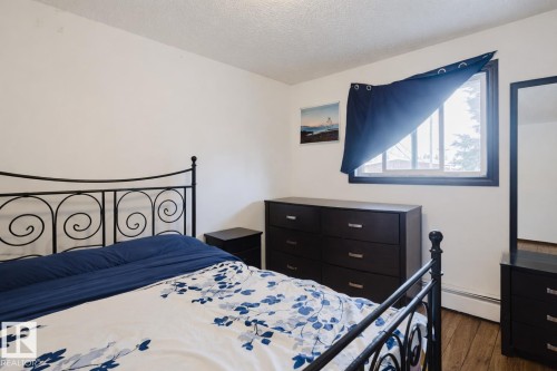 Bedroom with a textured ceiling, dark wood-type flooring, and a baseboard heating unit - 3917/3919 54 Street, Wetaskiwin, AB - Indoor Photo Showing Bedroom