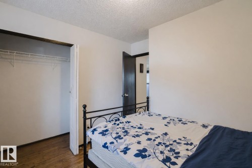 Bedroom featuring dark wood-style flooring, a textured ceiling, and a closet - 3917/3919 54 Street, Wetaskiwin, AB - Indoor Photo Showing Bedroom