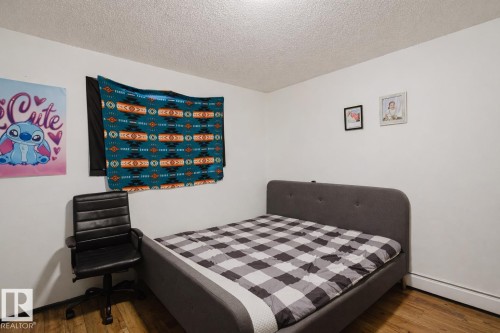Bedroom featuring a textured ceiling, a baseboard radiator, and wood finished floors - 3917/3919 54 Street, Wetaskiwin, AB - Indoor Photo Showing Bedroom