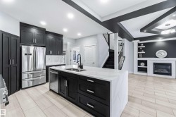 Kitchen with dark cabinets, built in features, a glass covered fireplace, appliances with stainless steel finishes, and open floor plan - 
