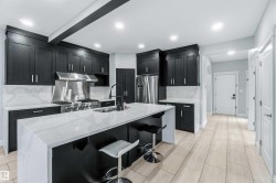Kitchen with dark cabinets, tasteful backsplash, light stone counters, a breakfast bar, and stainless steel appliances - 