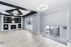 Unfurnished living room with built in shelves, a glass covered fireplace, and a tray ceiling - 