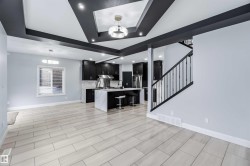 Kitchen featuring dark cabinetry, a breakfast bar area, a center island with sink, open floor plan, and light stone counters - 