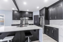 Kitchen with light stone counters, stainless steel fridge, beam ceiling, a breakfast bar area, and backsplash - 