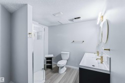 Full bathroom with double vanity, a stall shower, a textured ceiling, and light wood-style flooring - 