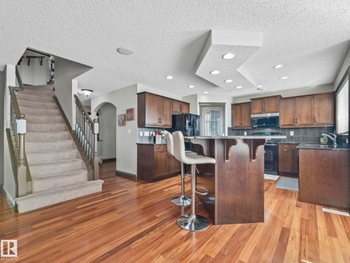 Kitchen featuring arched walkways, a breakfast bar area, a textured ceiling, black appliances, and tasteful backsplash - 960 Summerside Link, Edmonton, AB - Indoor Photo Showing Kitchen
