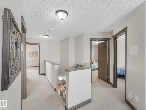 Hall featuring an upstairs landing, light carpet, and a textured ceiling - 960 Summerside Link, Edmonton, AB - Indoor Photo Showing Other Room