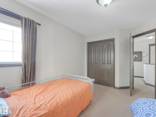 Carpeted bedroom featuring a textured ceiling and a closet - 960 Summerside Link, Edmonton, AB - Indoor Photo Showing Bedroom