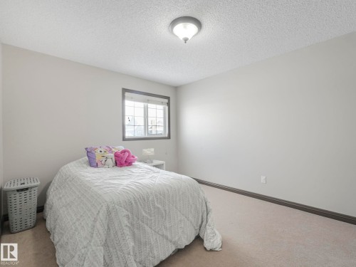 Carpeted bedroom featuring a textured ceiling and baseboards - 960 Summerside Link, Edmonton, AB - Indoor Photo Showing Bedroom