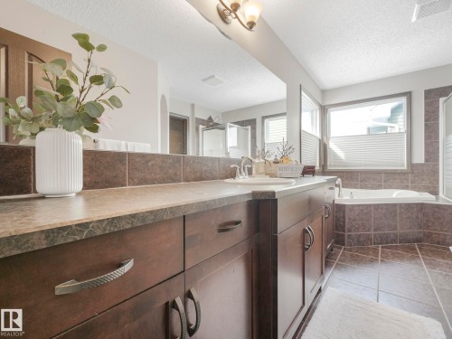Bathroom with vanity, a bath, a textured ceiling, light tile patterned floors, and a stall shower - 960 Summerside Link, Edmonton, AB - Indoor Photo Showing Bathroom
