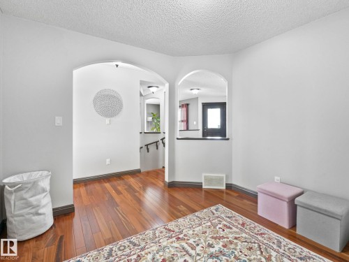 Empty room with dark wood-type flooring, arched walkways, and a textured ceiling - 960 Summerside Link, Edmonton, AB - Indoor Photo Showing Other Room