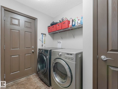 Laundry area with a textured ceiling and washing machine and clothes dryer - 960 Summerside Link, Edmonton, AB - Indoor Photo Showing Laundry Room