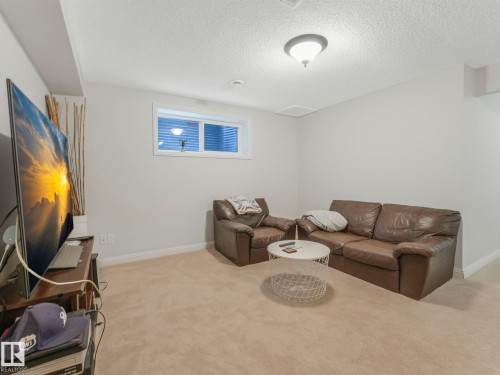 Living area with light carpet and a textured ceiling - 960 Summerside Link, Edmonton, AB - Indoor