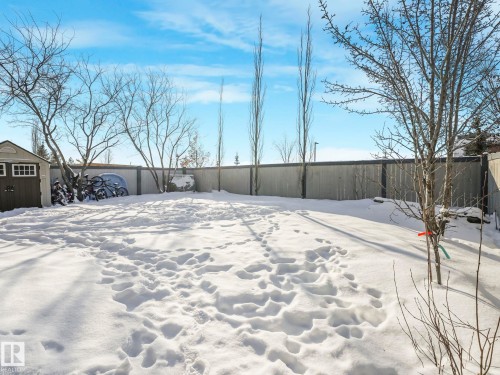 Snow covered patio with a fenced backyard and a storage unit - 960 Summerside Link, Edmonton, AB - Outdoor