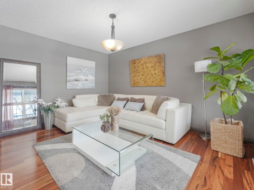 Living room featuring dark wood-style flooring and a textured ceiling - 960 Summerside Link, Edmonton, AB - Indoor Photo Showing Living Room