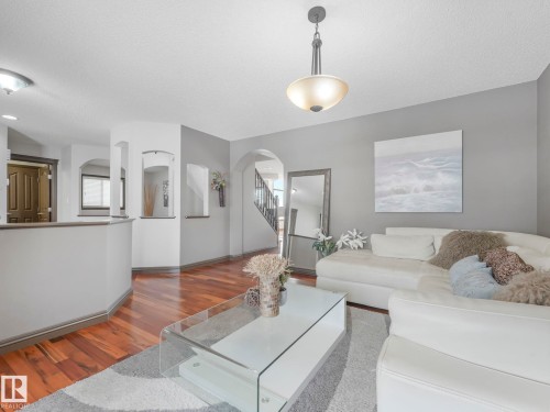 Living room featuring wood finished floors, a textured ceiling, and arched walkways - 960 Summerside Link, Edmonton, AB - Indoor Photo Showing Living Room